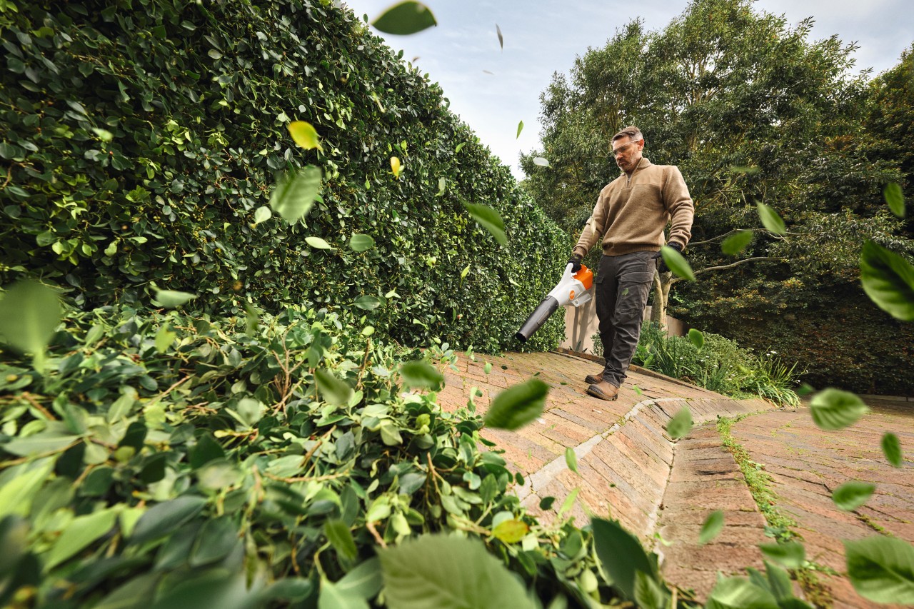 Man using STIHL leaf blower to tidy garden