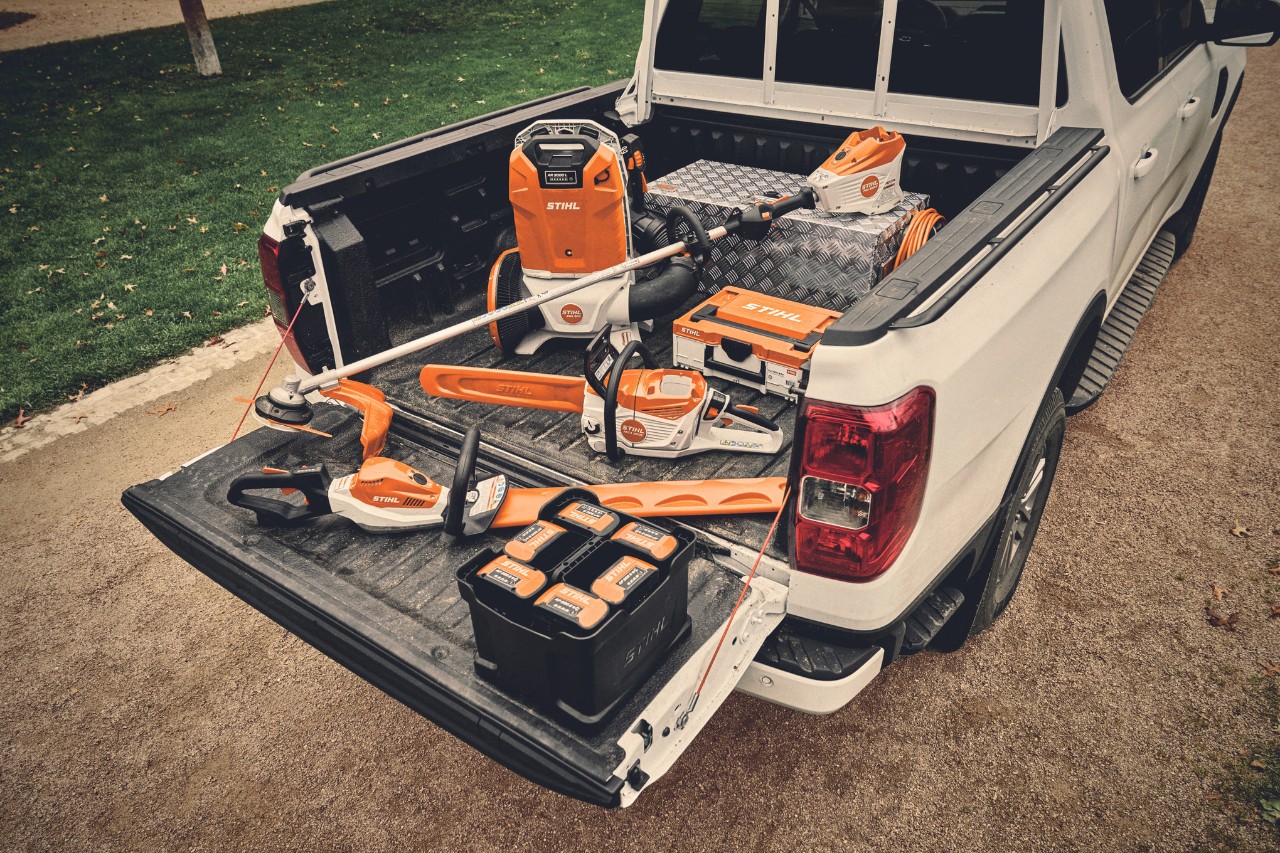 Various battery-powered tools from the STIHL AP system and the matching batteries on the loading area of a vehicle