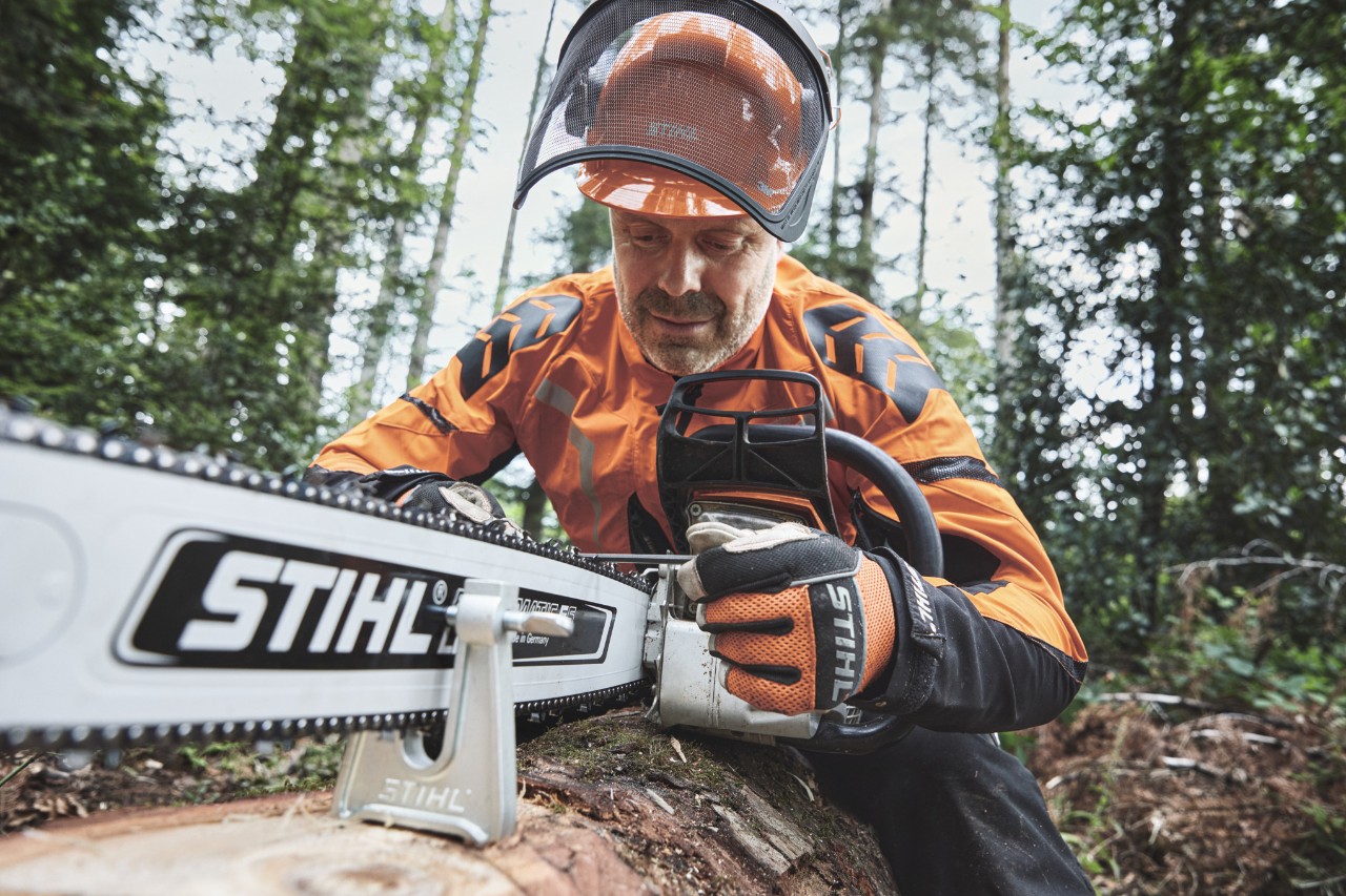 A man wearing protective equipment working with a STIHL chainsaw in a forest