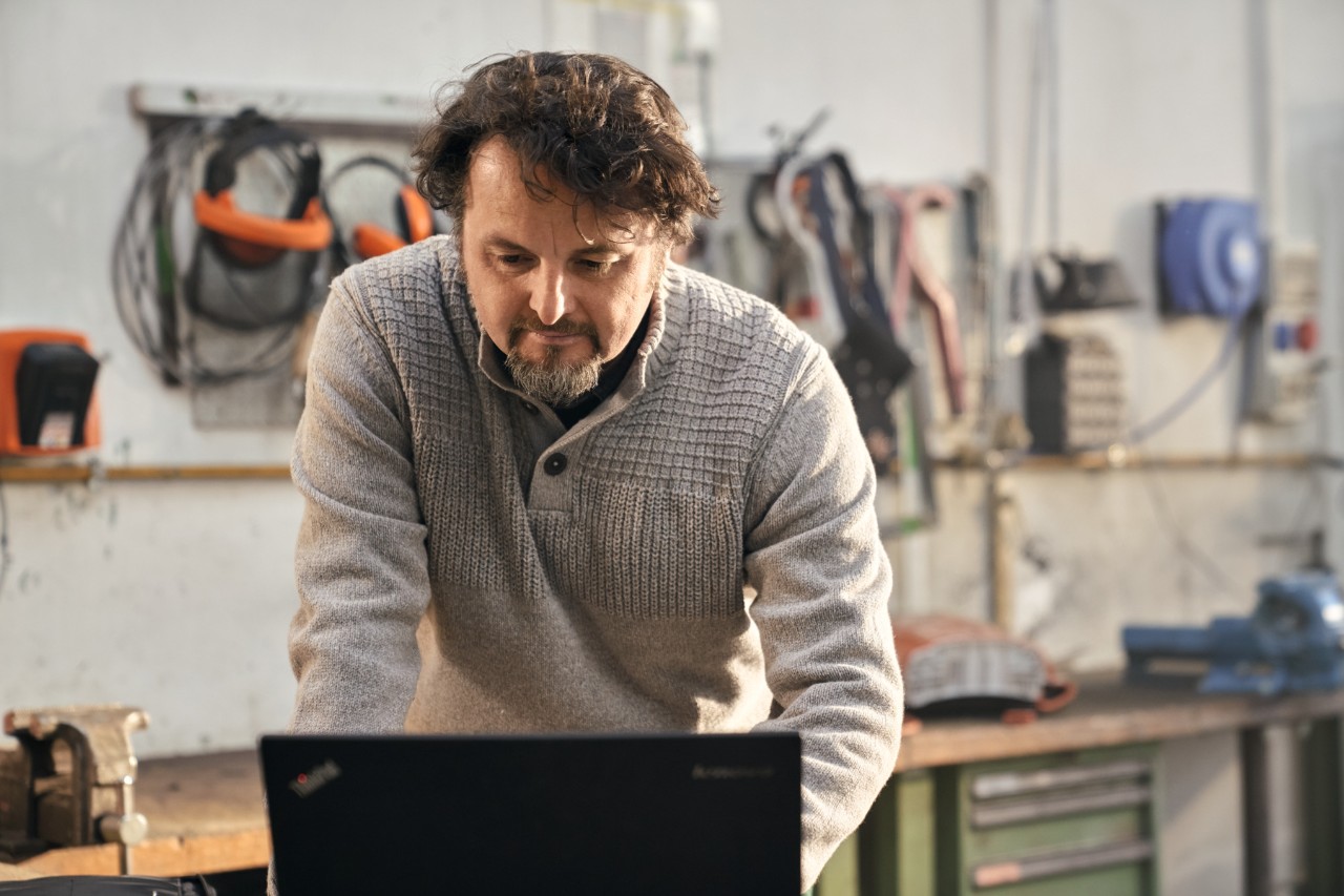 A man using a laptop in a workshop.