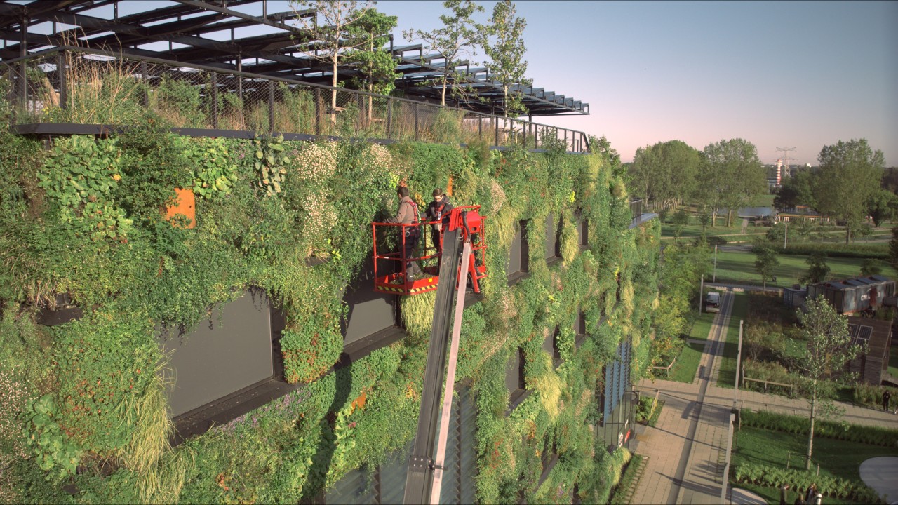 Two workers on a lifting platform take care of the greenery on the Aeres Hogeschool campus 