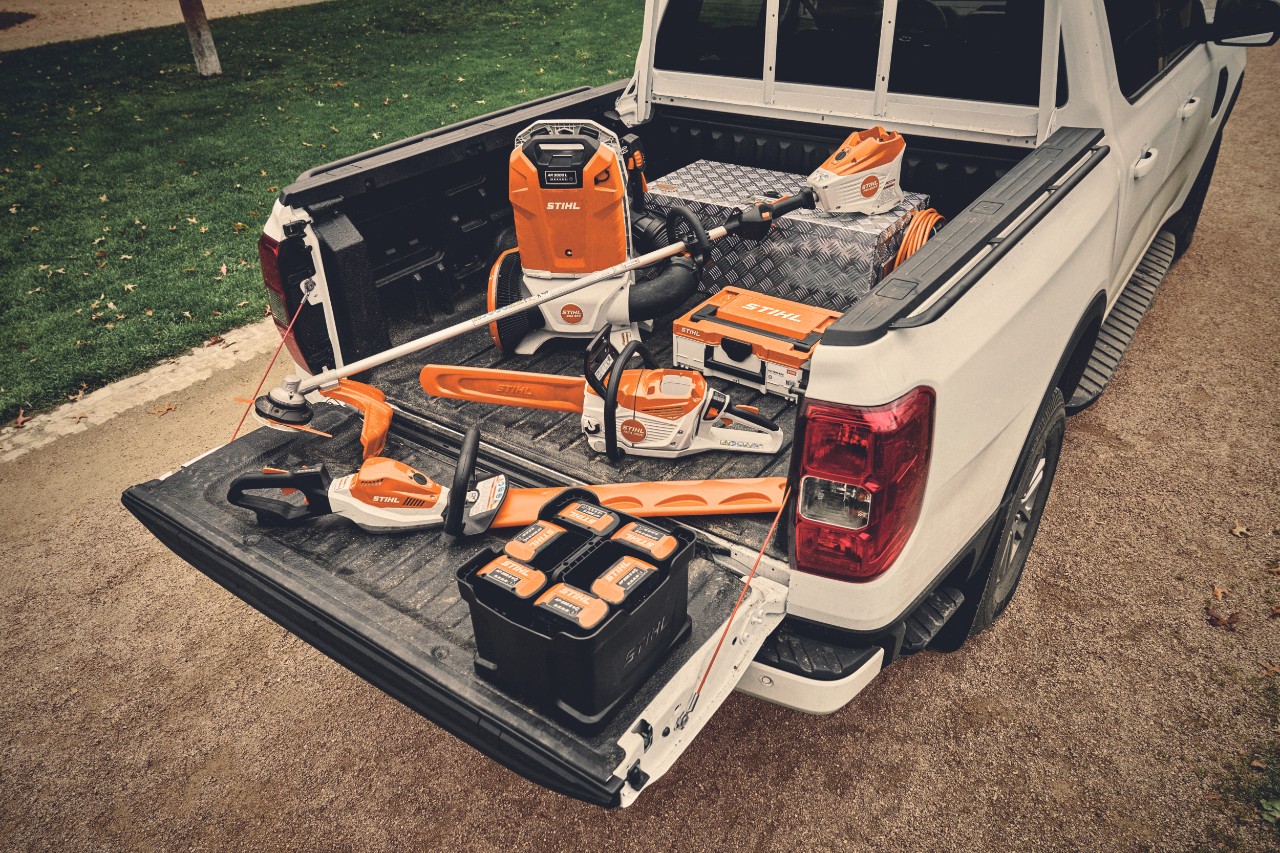 Various battery-powered tools from the STIHL AP system and the matching batteries on the loading area of a vehicle