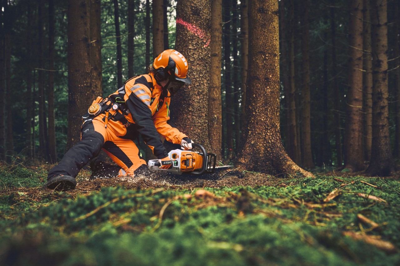 Forestry worker in STIHL ADVANCE FlexTEC ShellTEC PPE cuts down a tree with a STIHL chainsaw