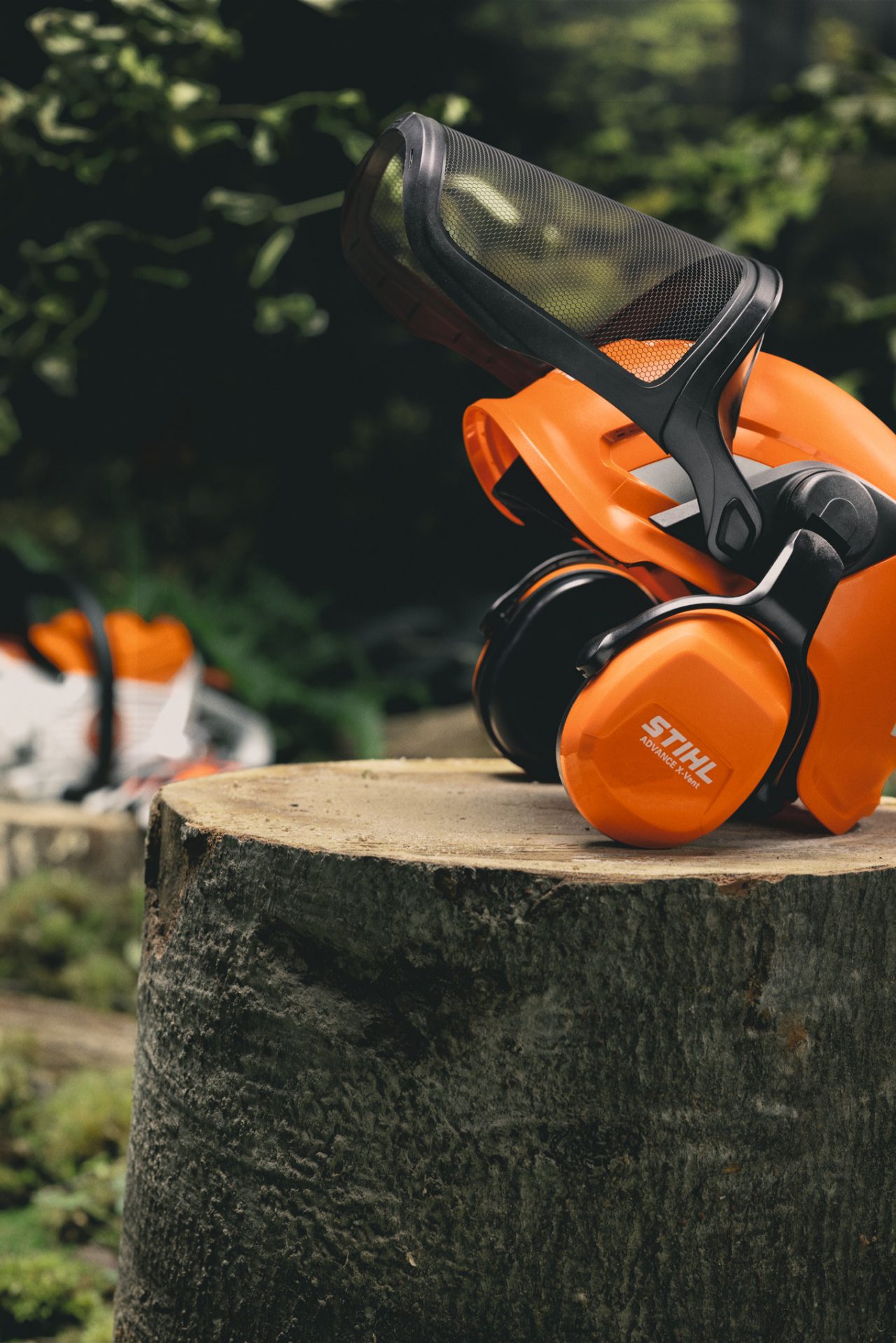 Close-up of the STIHL Advance X-Vent ProCom helmet set on a tree trunk
