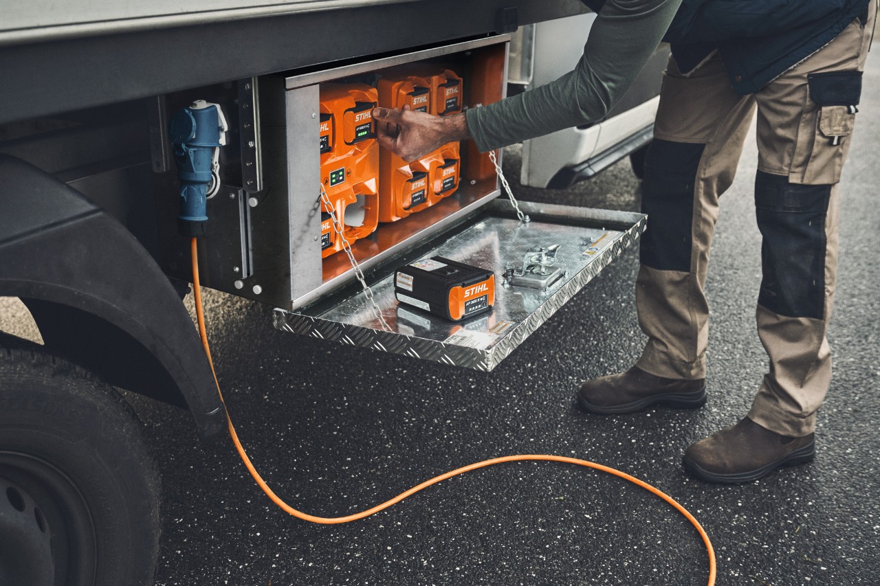 A man takes a charged STIHL AP 500 battery out of the charging box 