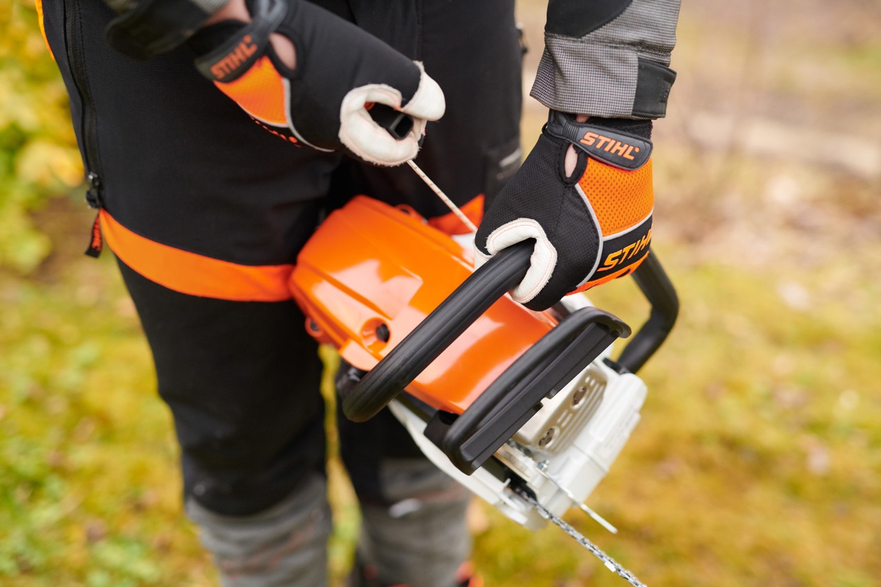 A STIHL MS 261 C-M petrol chainsaw being started by someone wearing protective clothing