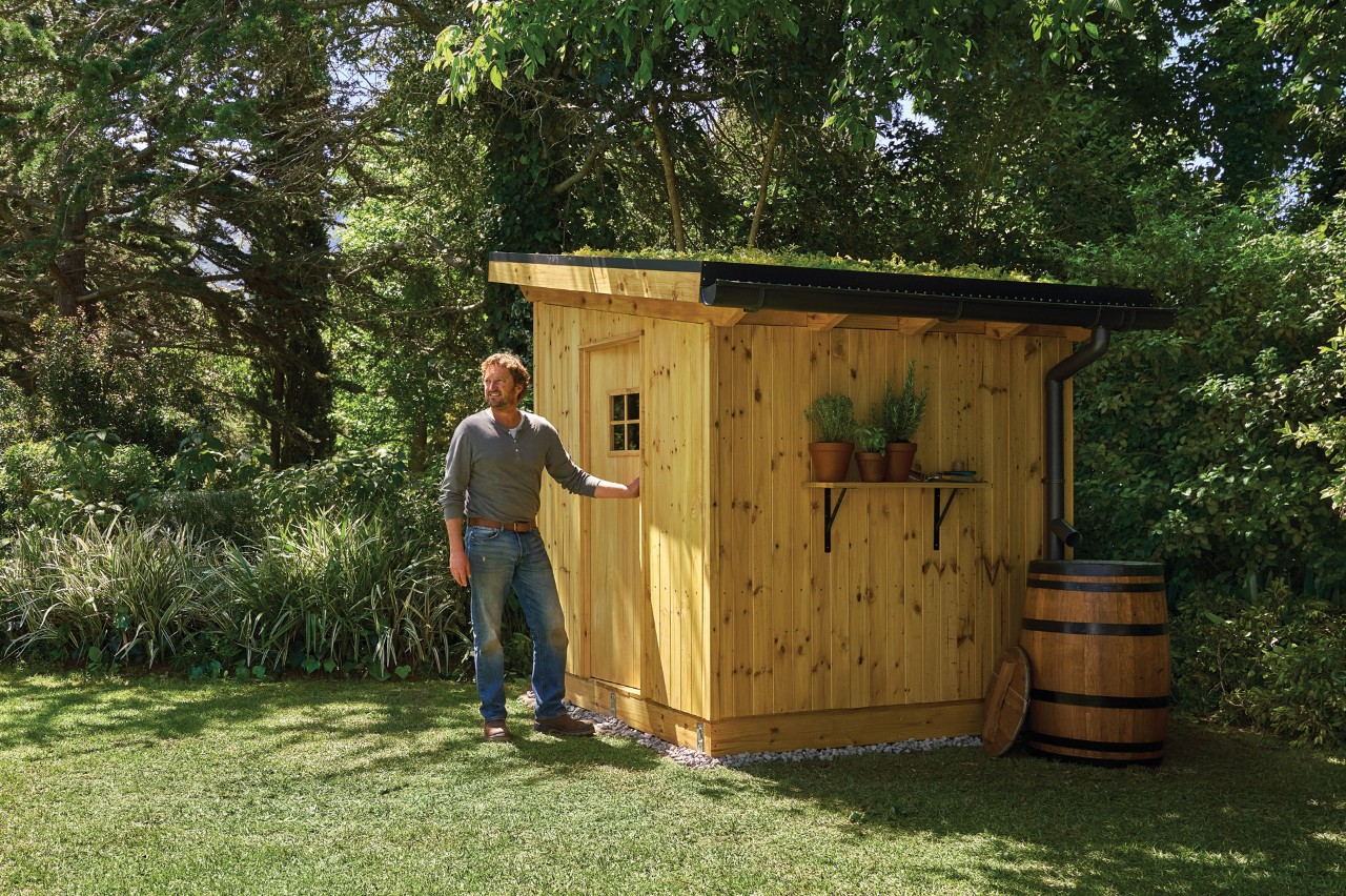a guide standing in front of a wooden shed in a garden