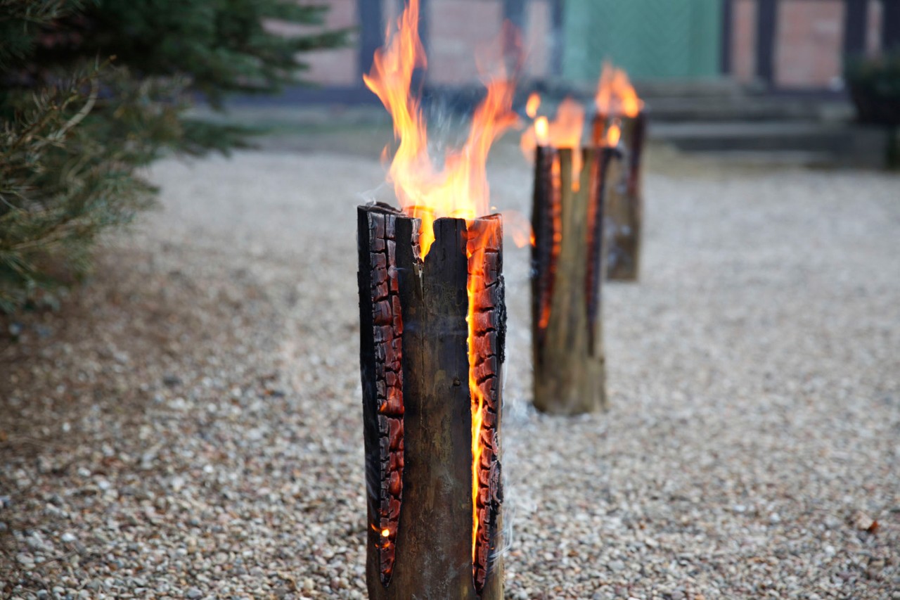 Three burning DIY Swedish fire logs on a gravel road