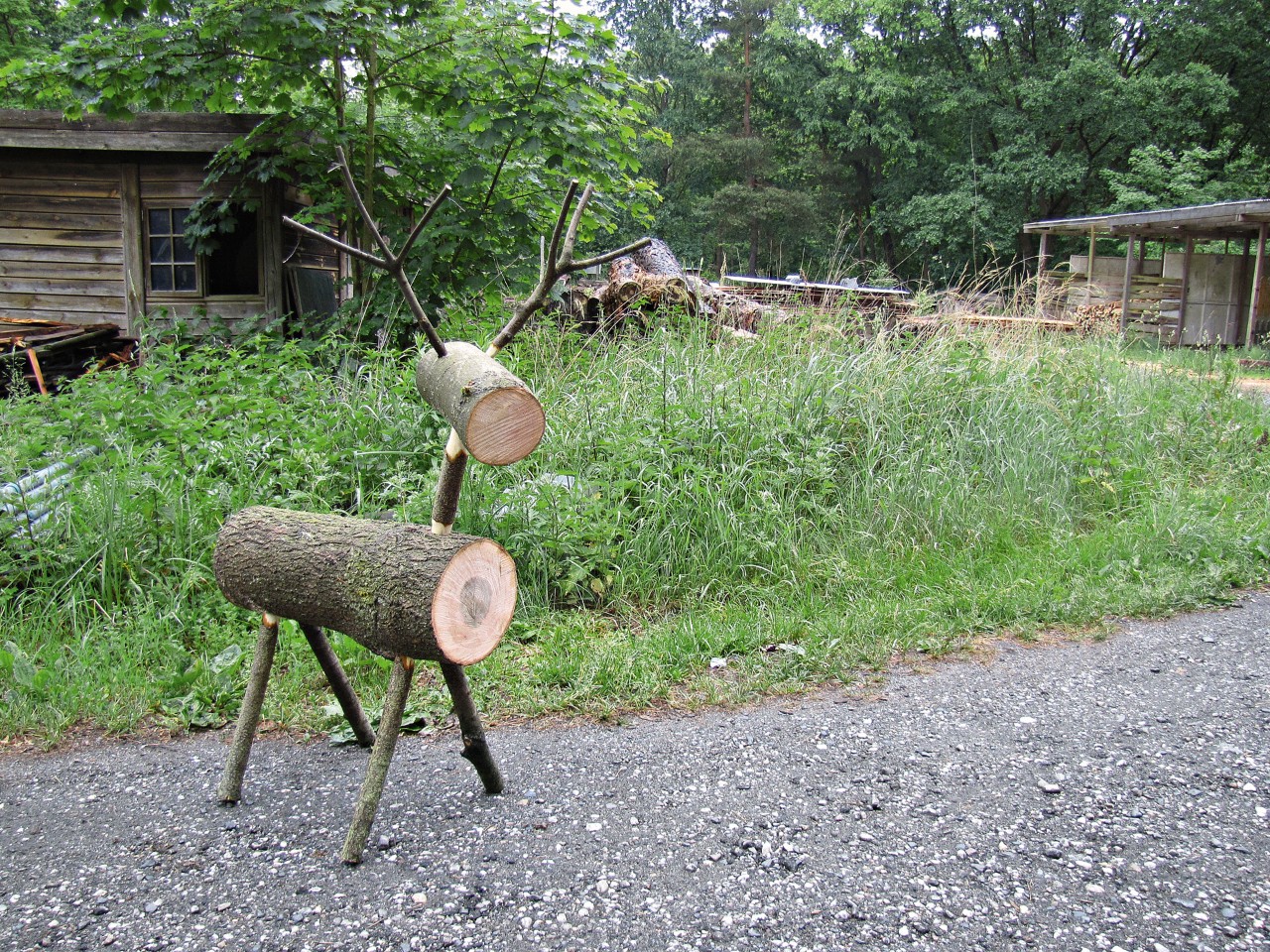 Wooden reindeer in front of green lawn and wooden hut
