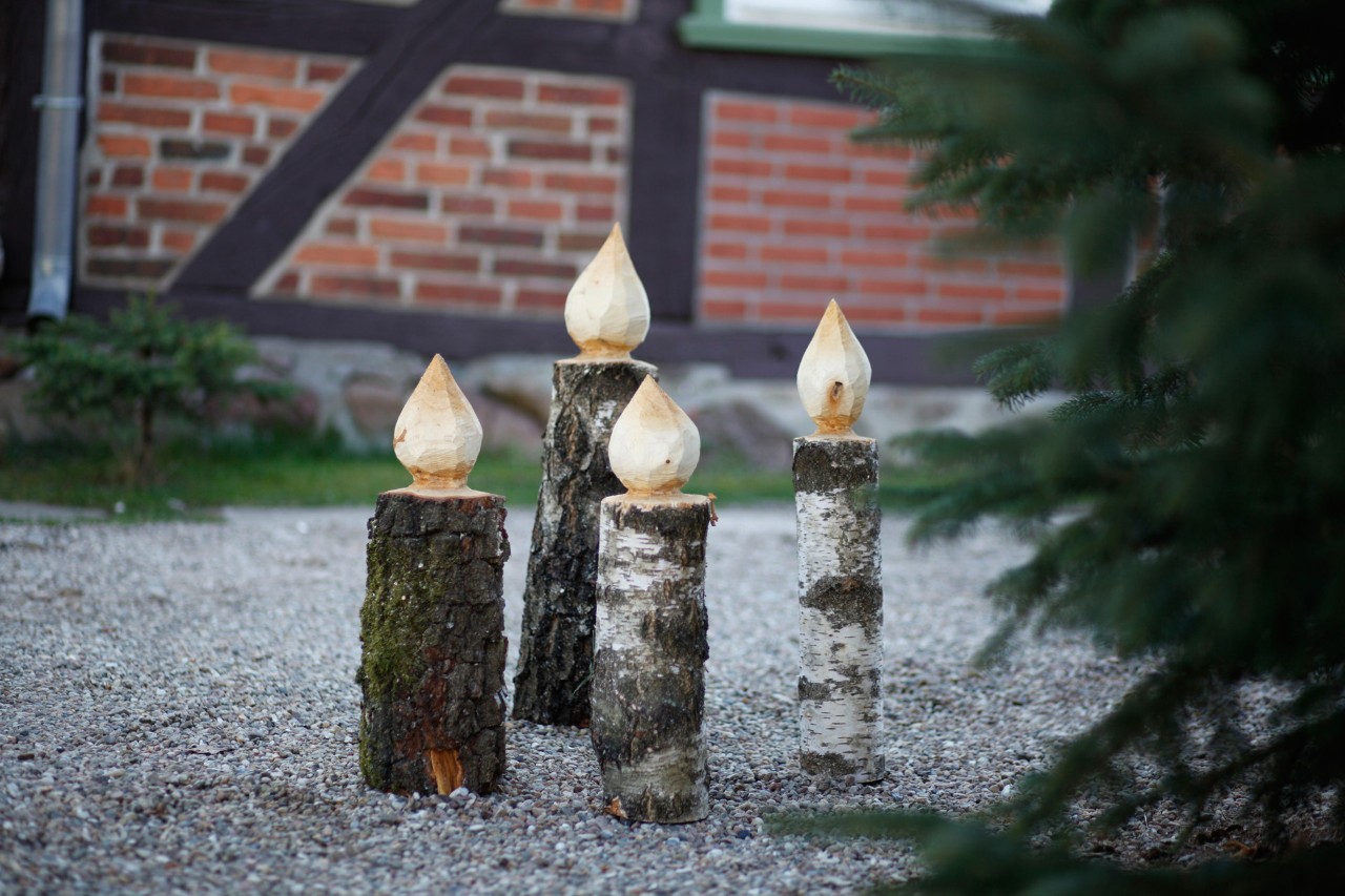 Four DIY wooden candles next to a Christmas tree