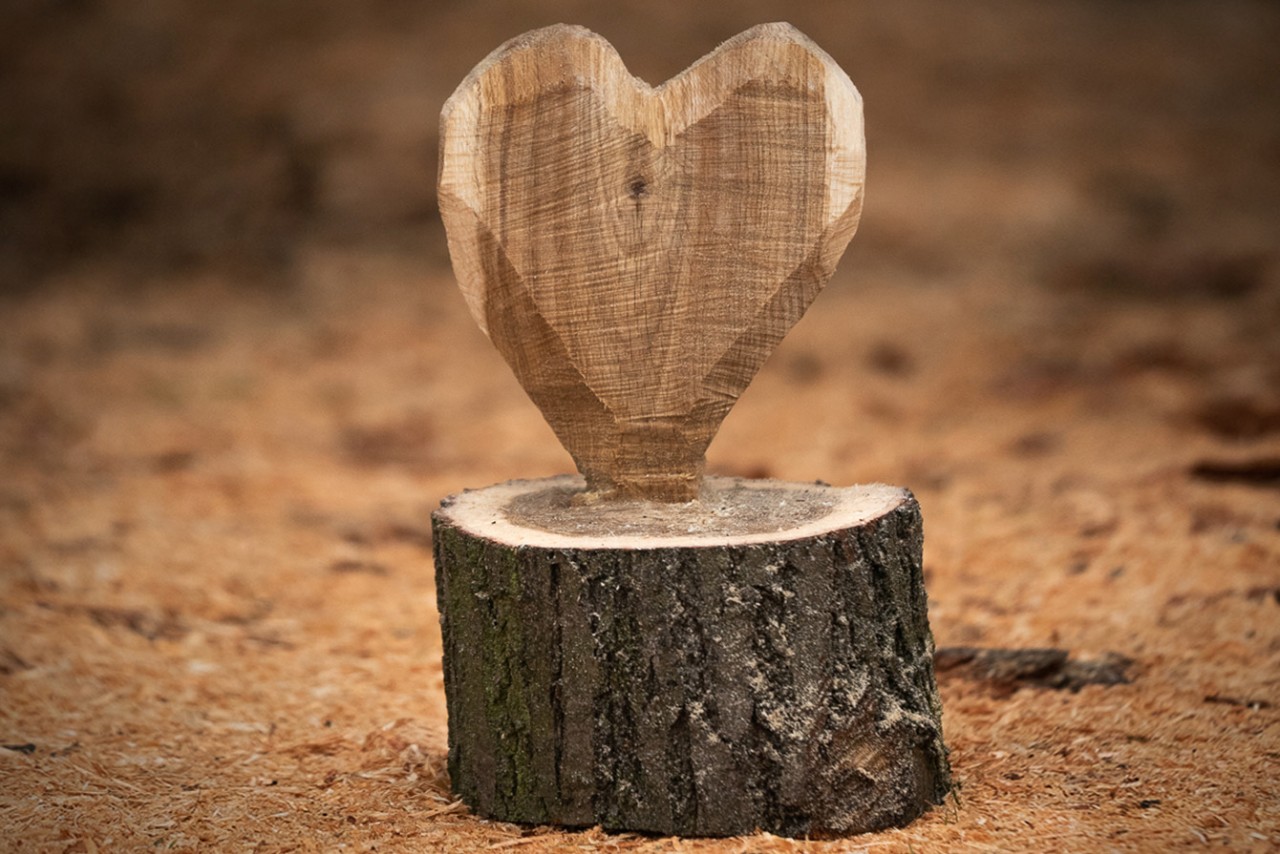 A DIY wooden heart stands on the floor surrounded by chips