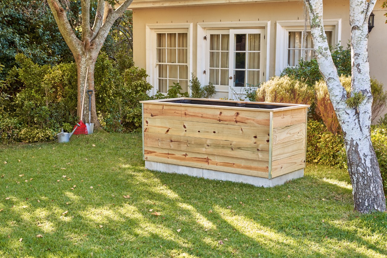 DIY wooden raised bed made from boards in the garden in front of a house