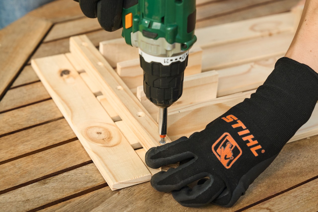 Close-up of someone pre-drilling holes wearing STIHL protective gloves