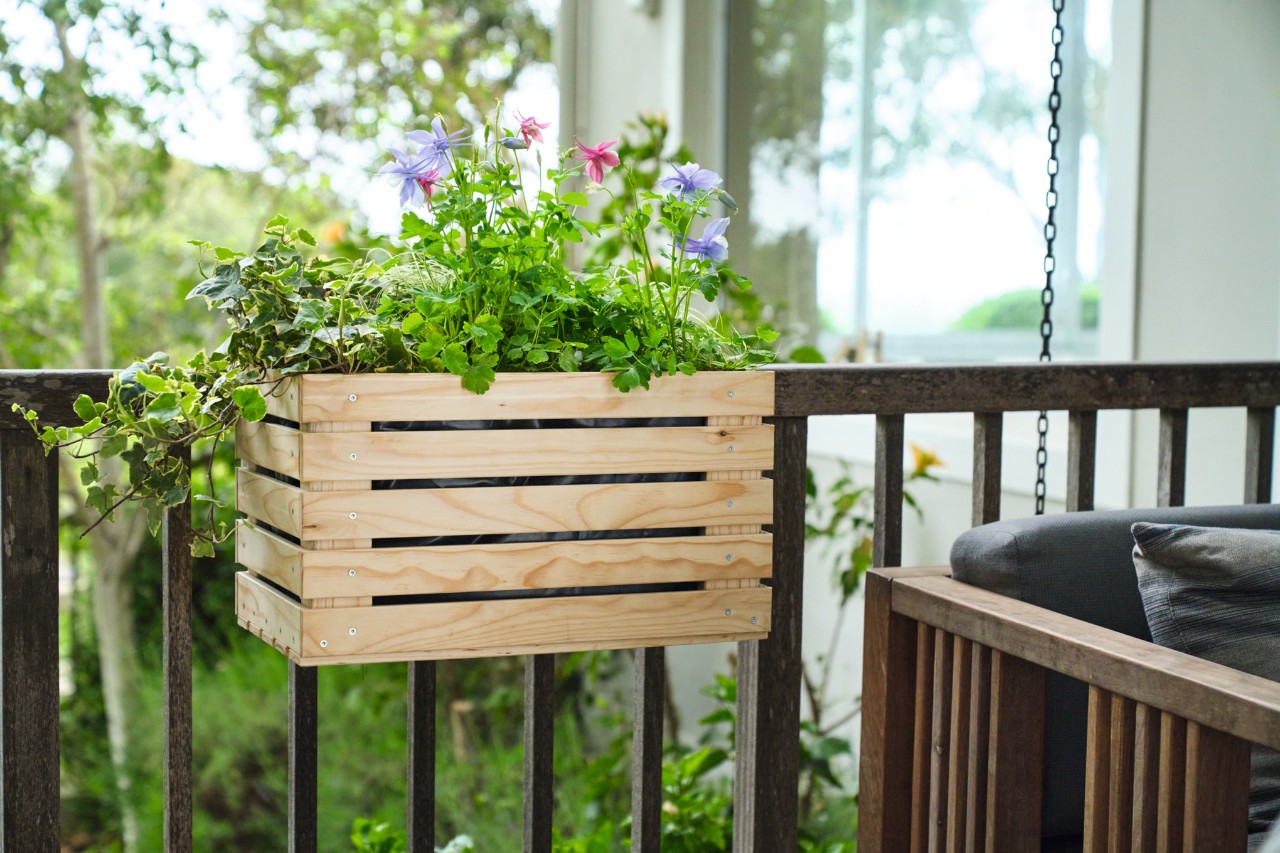 A planter with flowers hangs on a balcony railing