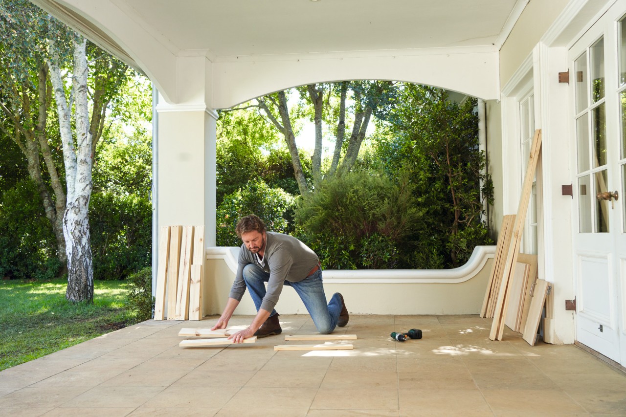A man on a terrace putting side panels in place for a potting bench