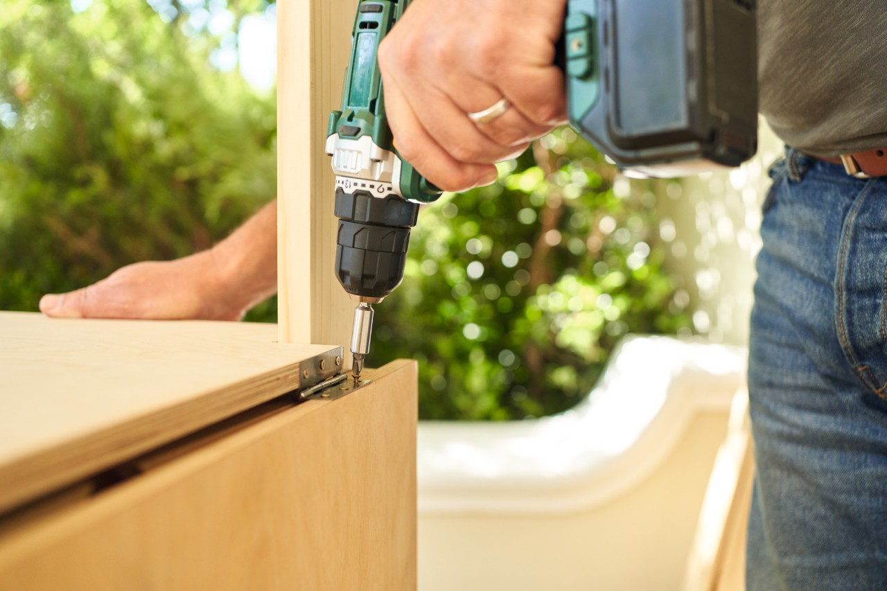 Close-up of someone using a screwdriver to attach an extension surface to a planting table 