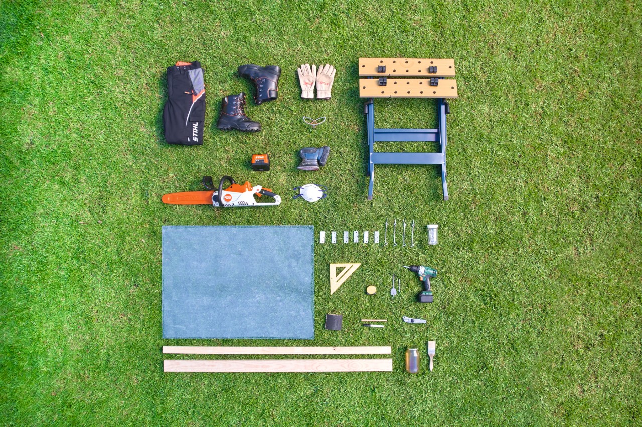 Material, tools and protective equipment to build a DIY raised bed cover arranged in a square on grass