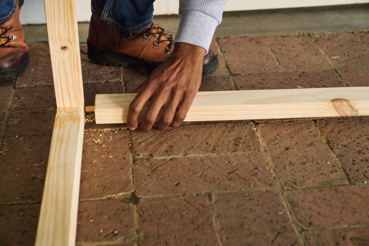 A person inserts the wooden dowels on the floor strut