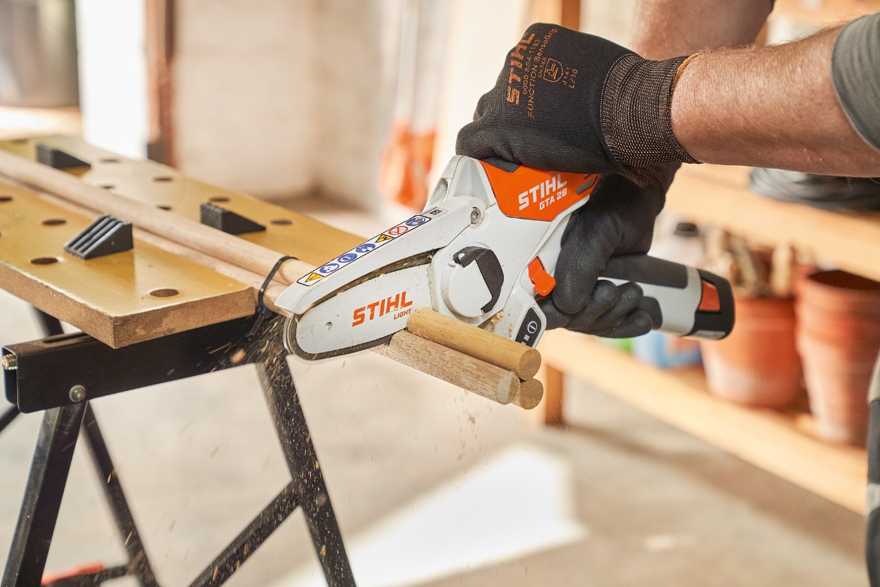 A man sawing round dowels with a STIHL GTA 26 cordless garden pruner