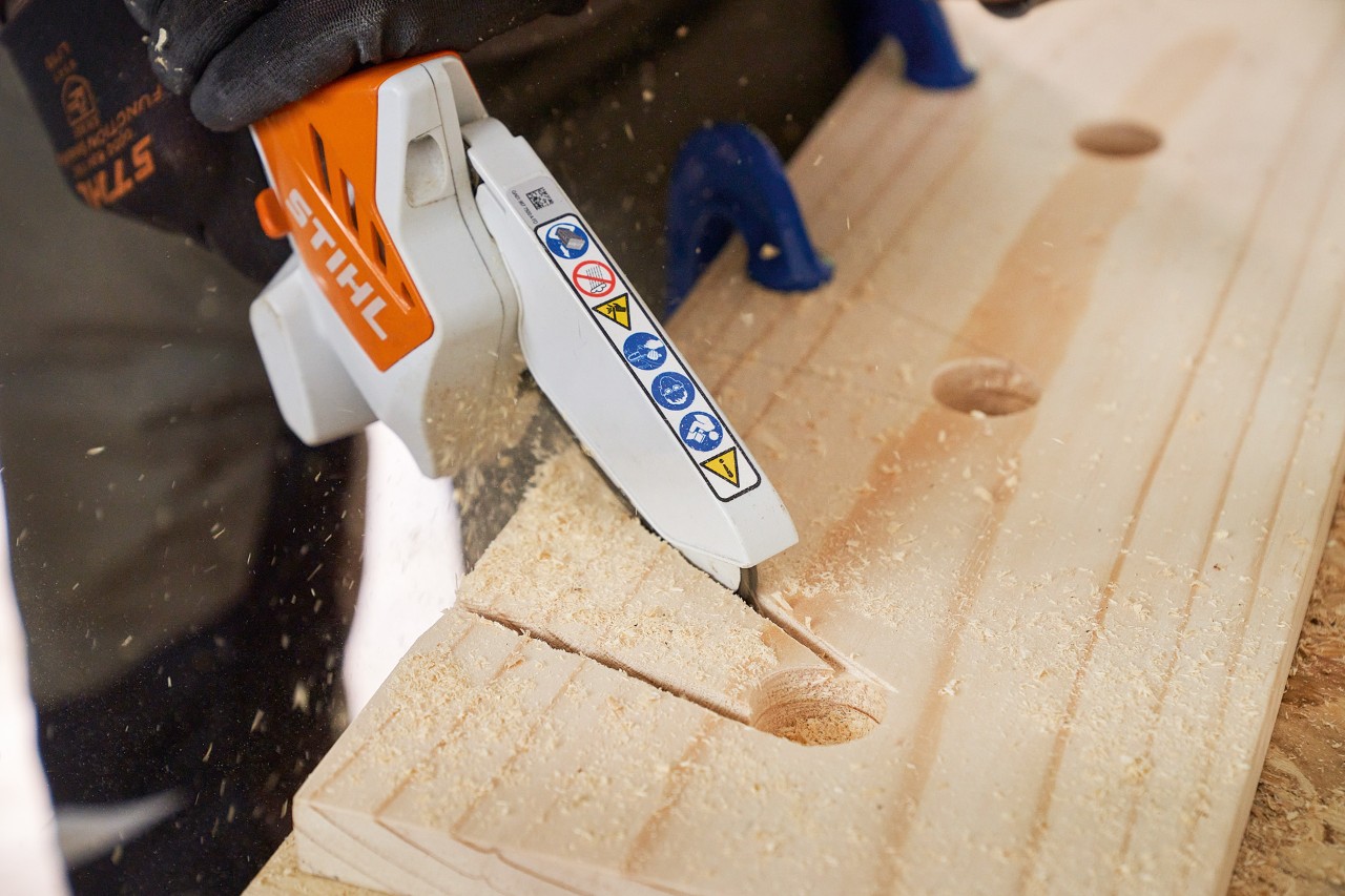 Someone sawing recesses into a wooden board with the STIHL GTA 26 cordless garden pruner
