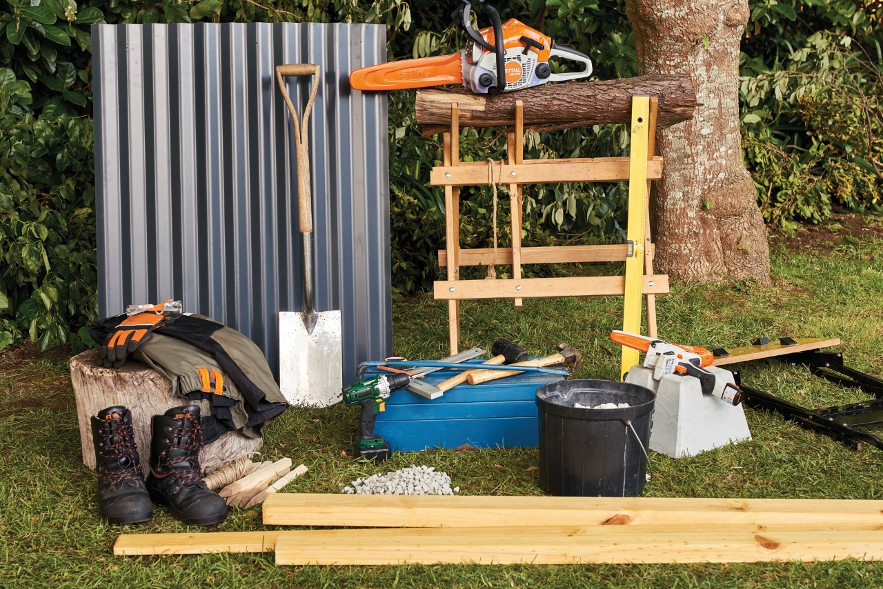 Necessary materials and equipment including the STIHL MSA 140 cordless chainsaw, a spade and workbench laid out on grass