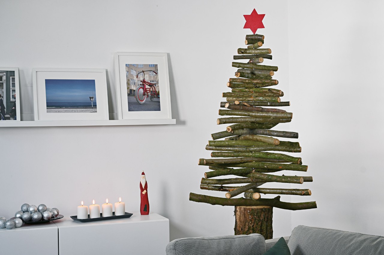 DIY Christmas tree made of wooden branches with a red star at the top in a room with Christmas decorations