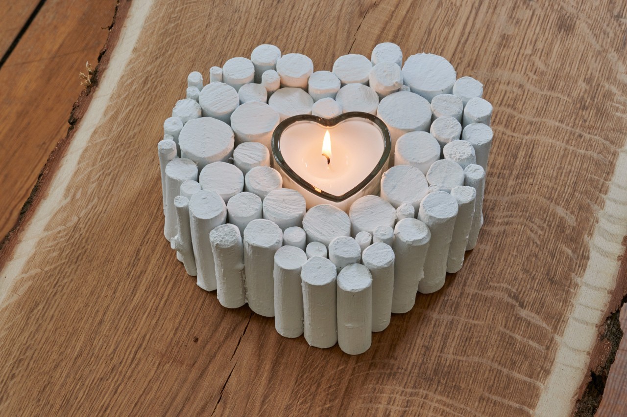 DIY heart ornament from a branch: finished ornament painted white, with a lit candle inside