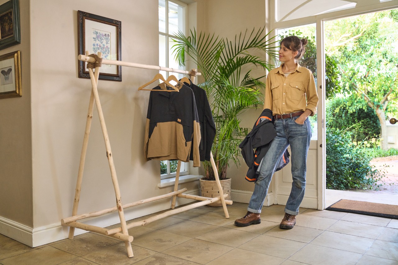 A smiling woman stands in front of a DIY wooden clothes rack