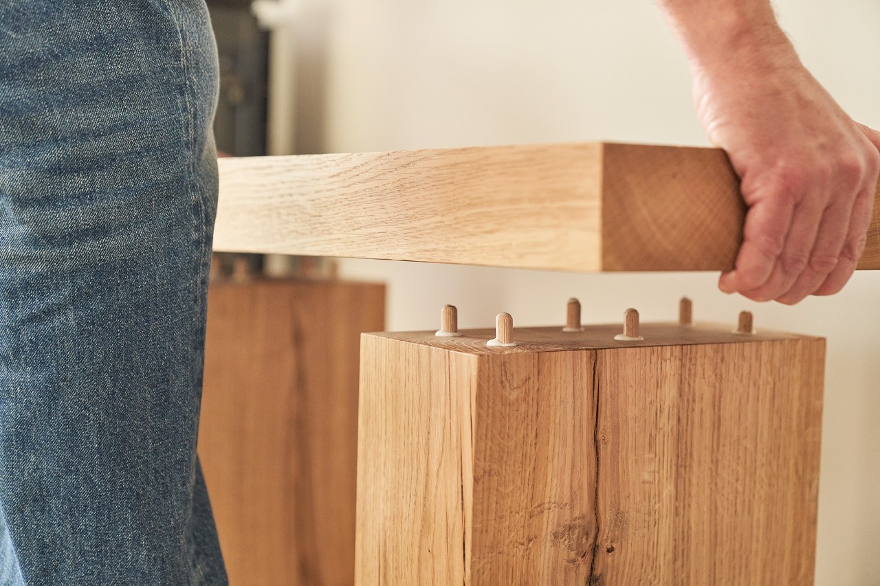 A person attaching wooden planks together with the aid of dowels