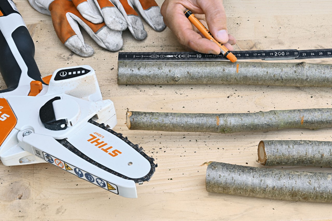 Marking suitable length sections on branches with an orange pen with protective gloves and the STIHL GTA 26 cordless garden pruner nearby 