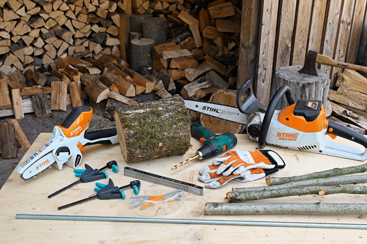 Materials and tools for making a DIY wooden Christmas tree, including the STIHL MSA 120 cordless chainsaw and the STIHL GTA 26 cordless garden pruner 