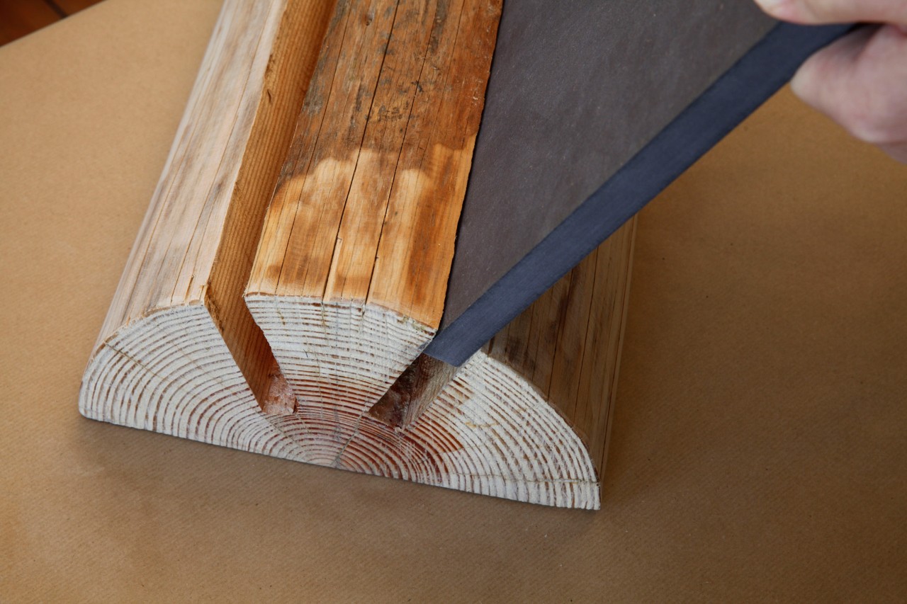 An MDF board being slotted into one the slots cut into a split log 