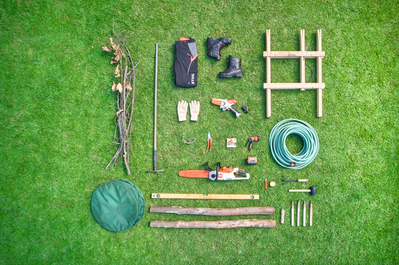 Aerial view of the material and tools required to create a dead hedge, arranged on a lawn