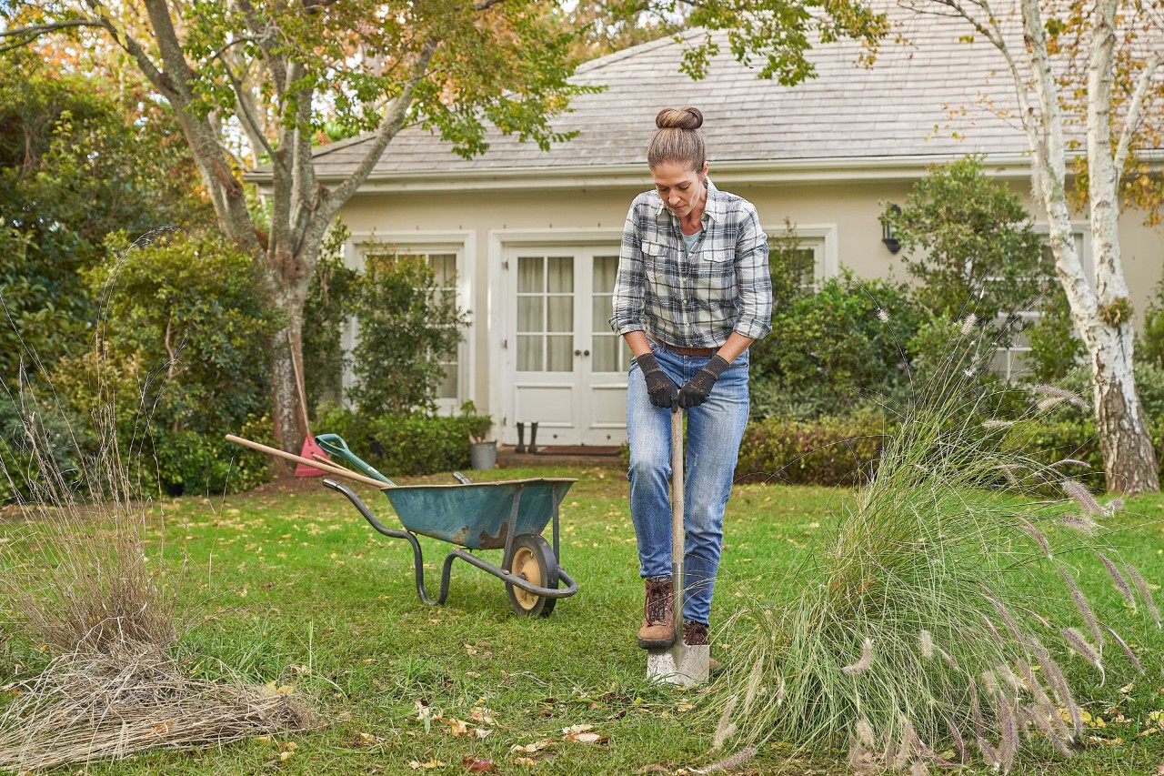A woman wearing STIHL Function SensoTouch protective gloves working with a spade to prepare for planting a hedge 