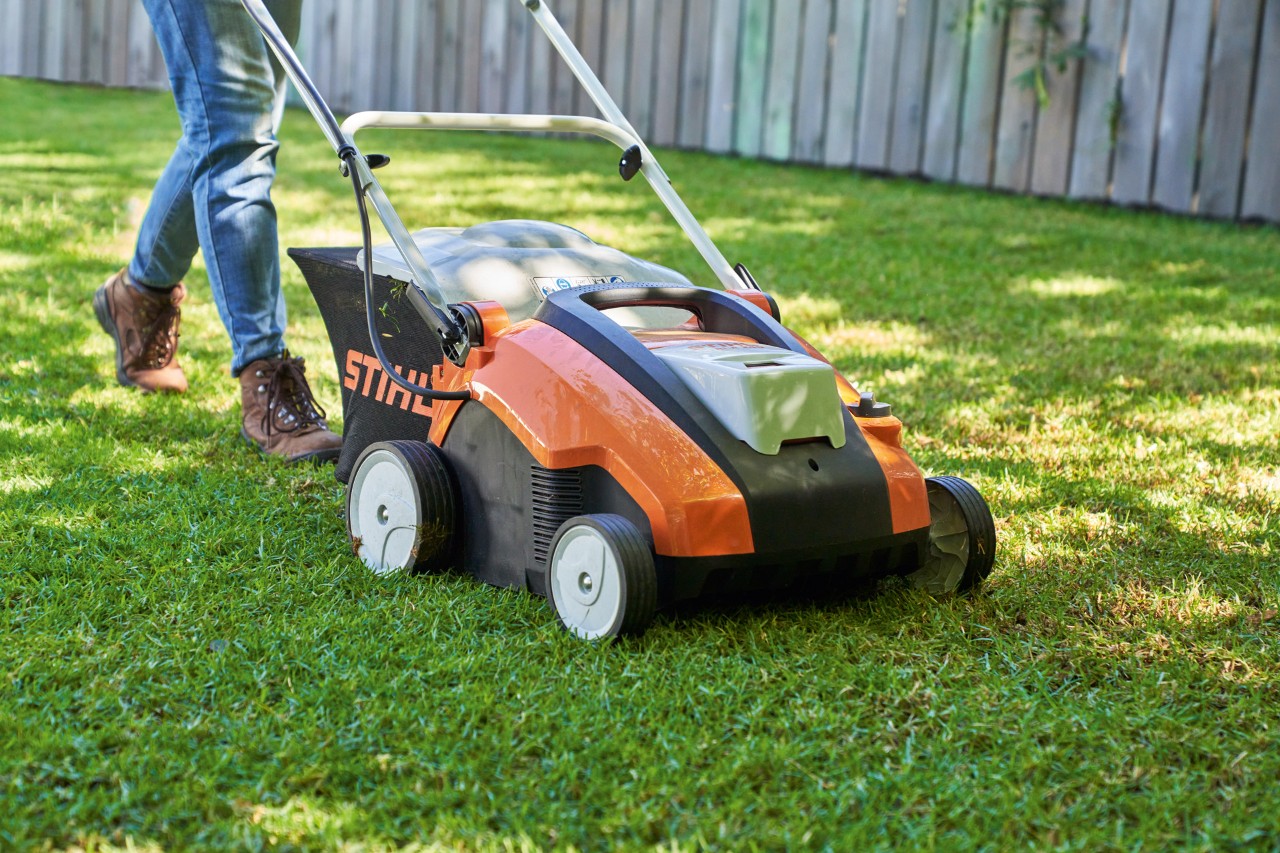 STIHL RLA 240 cordless lawn aerator being used to aerate a green lawn.