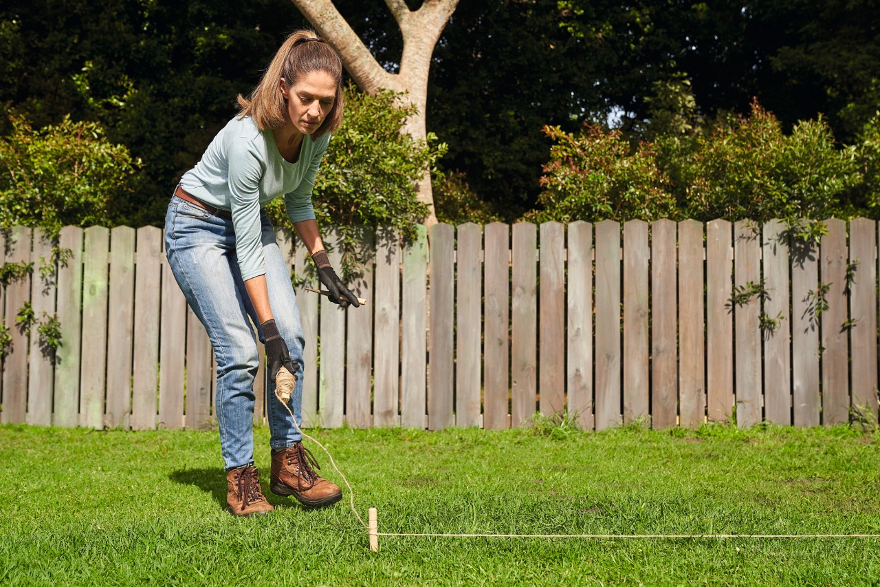 Woman staking out an area with pegs to lay turf 
