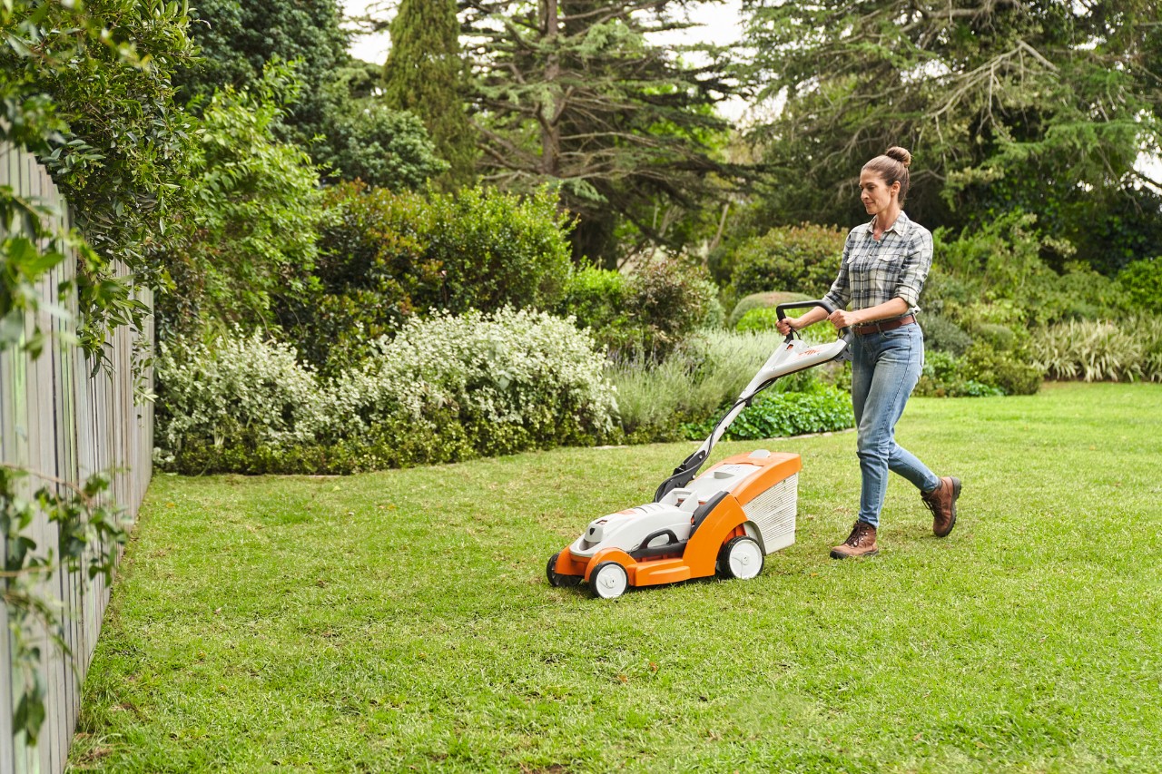 A woman mowing her self-laid lawn with a STIHL RMA 339 C cordless lawn mower