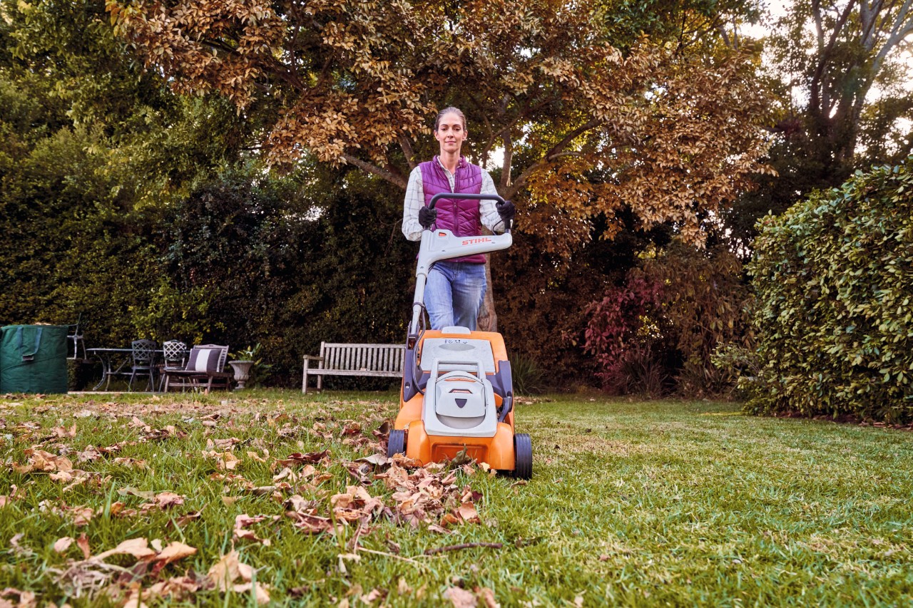 A woman using a STIHL RMA 339 battery lawn mower on a grass area