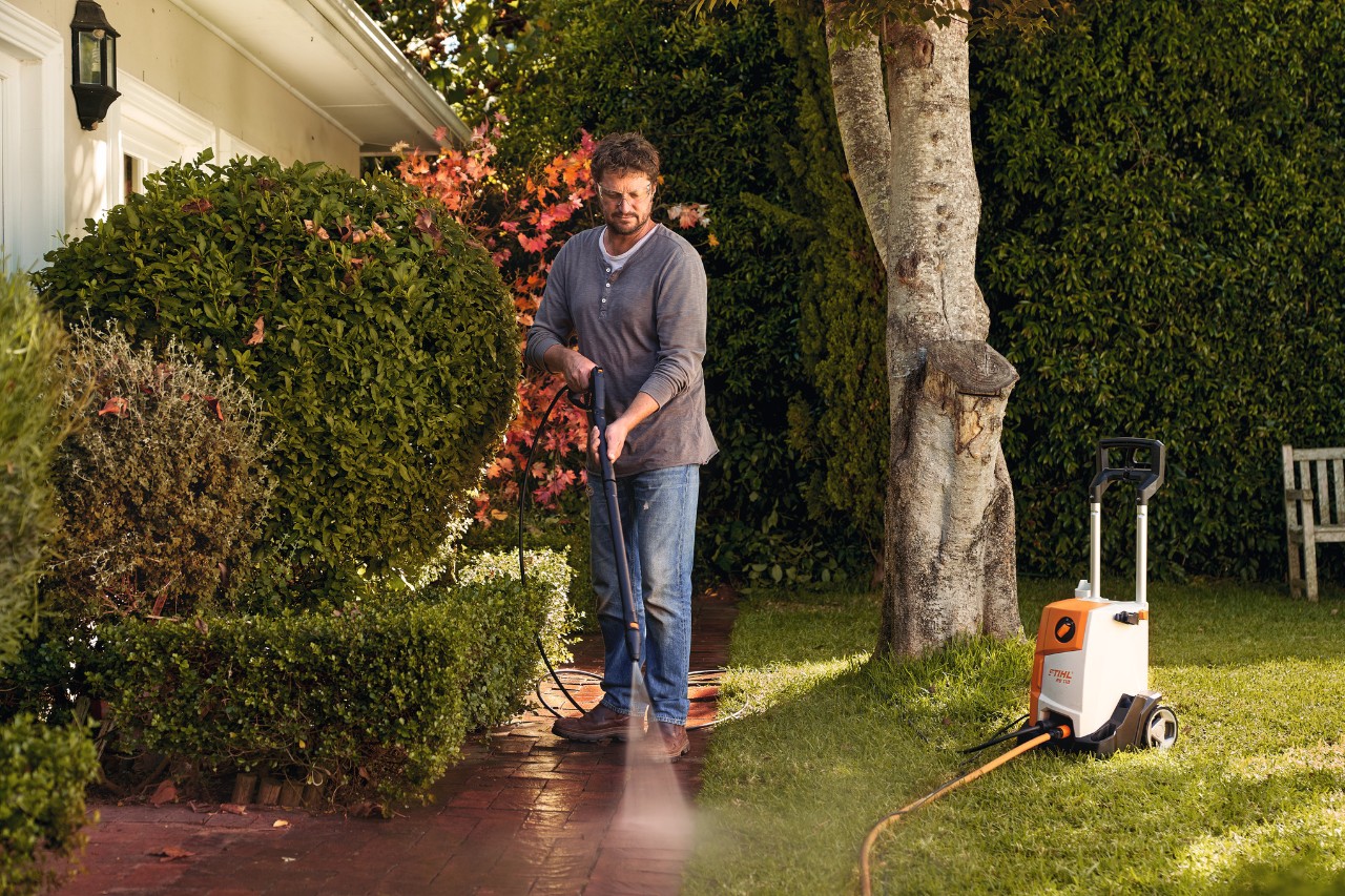 A man cleaning paving in front of his house with a STIHL RE 110 high-pressure cleaner