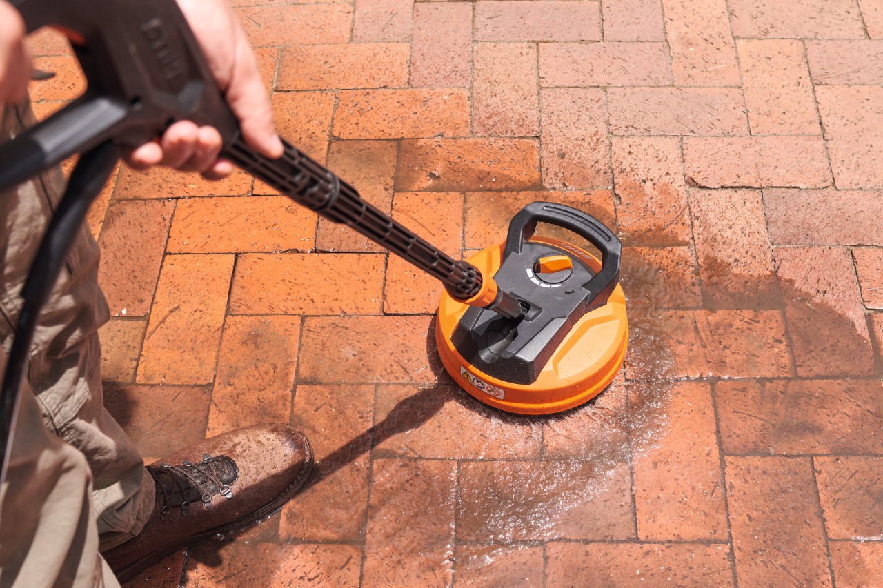 Person adding STIHL CS 100 Stone and Facade cleaner to foam nozzle to clean paving stones