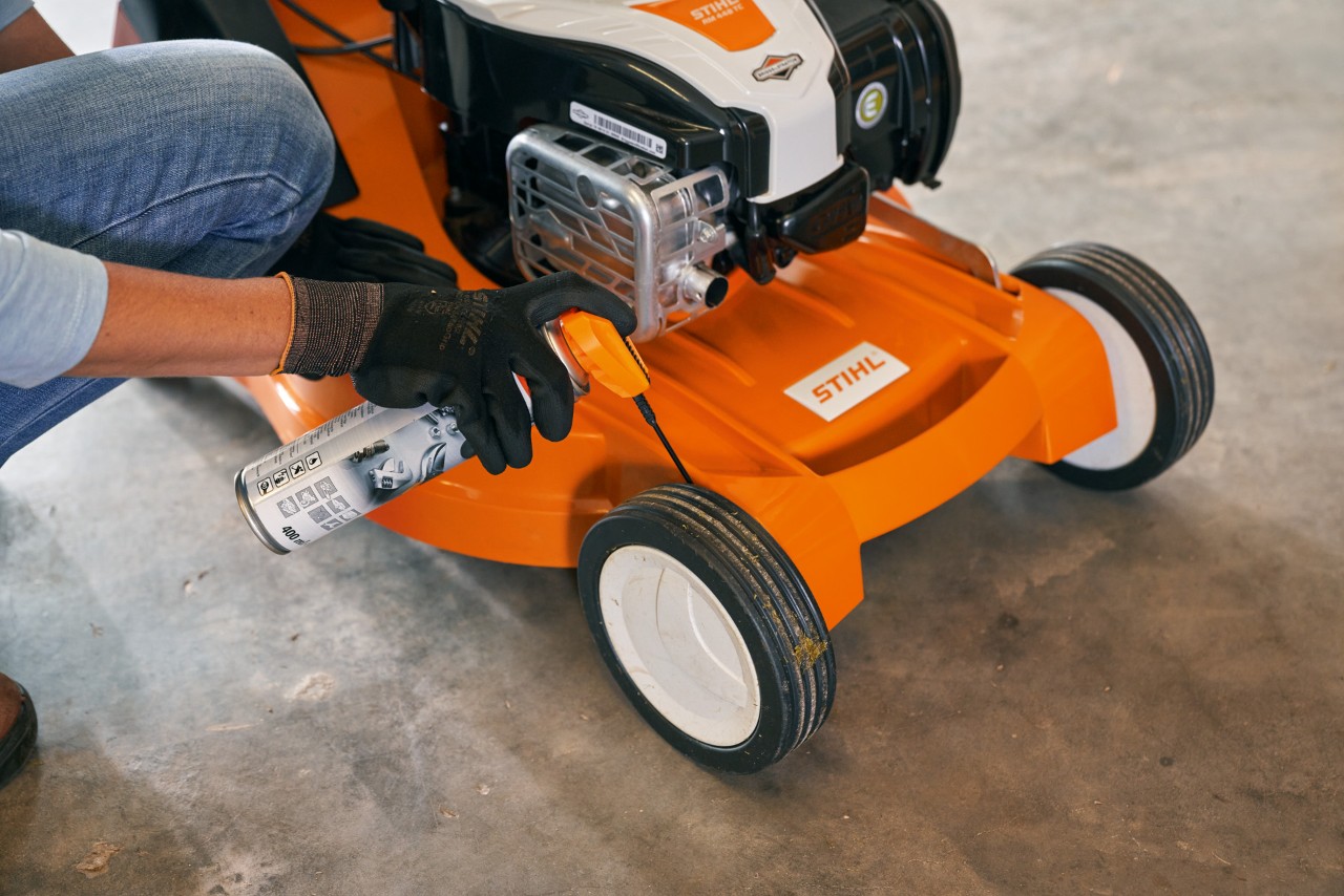 a person is maintening a STIHL lawn mower