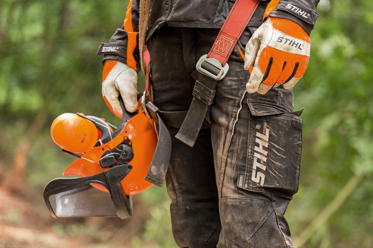 Person wearing STIHL protective clothing: work gloves, cut protection trousers and helmet set