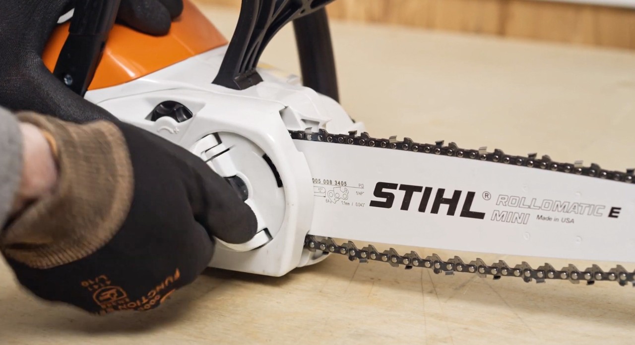 The sprocket cover on a STIHL MSA 120 cordless chainsaw being reinstalled