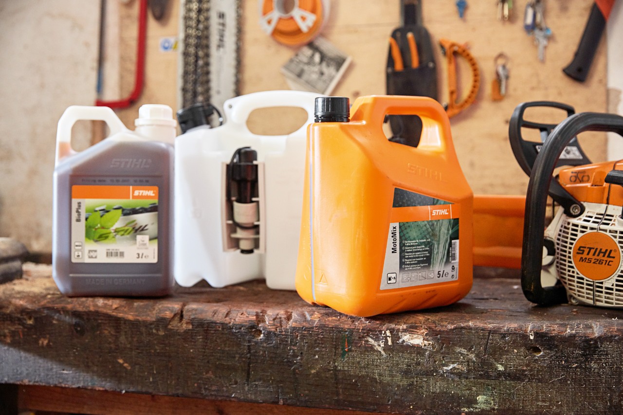 A combination canister on a bench between containers of STIHL MotoMix and BioPlus chain oil 