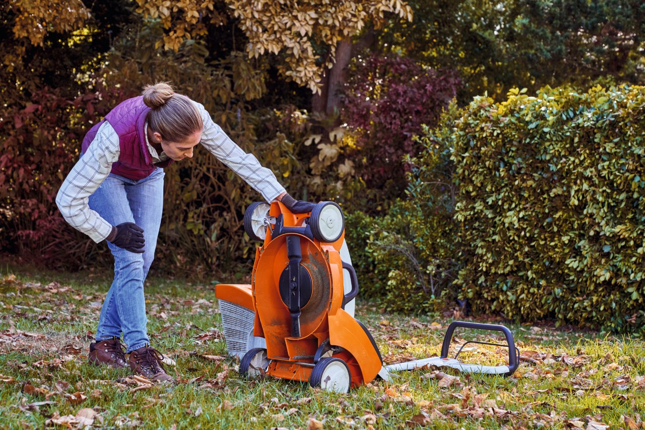 Woman inspecting underneath her lawn mower