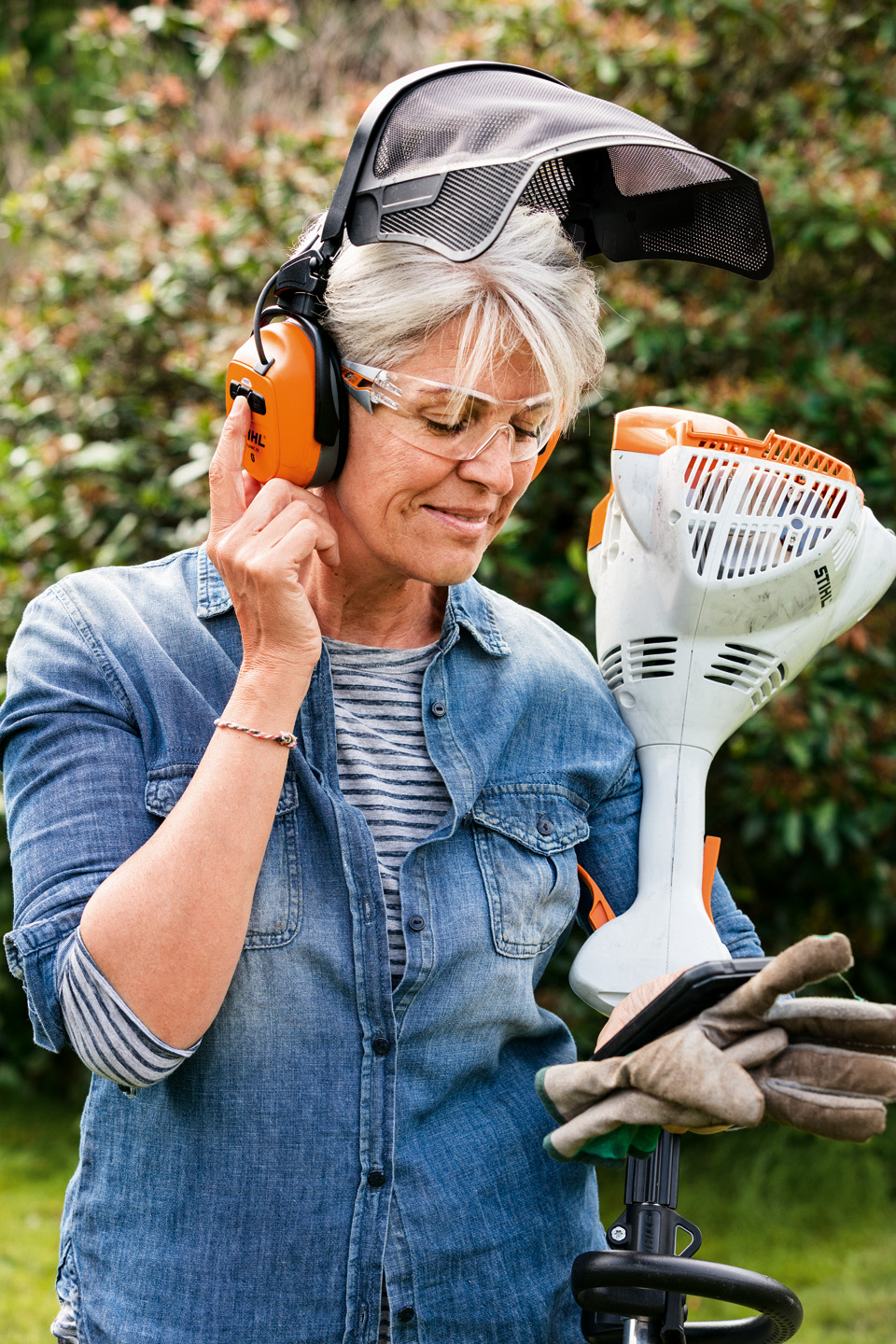 A woman wearing face/ear protection holding a STIHL FS 58 R brushcutter