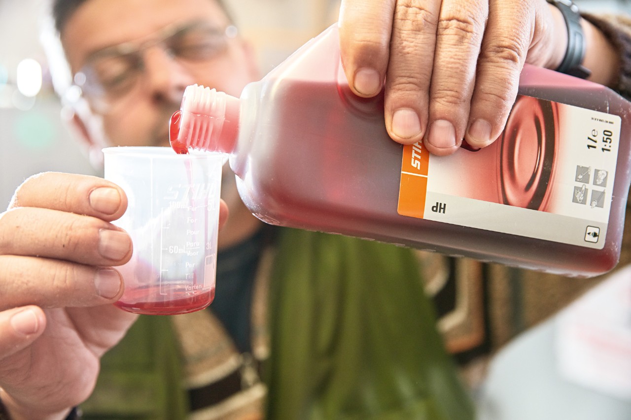 A man pours STIHL HP 2-stroke engine oil into a measuring beaker