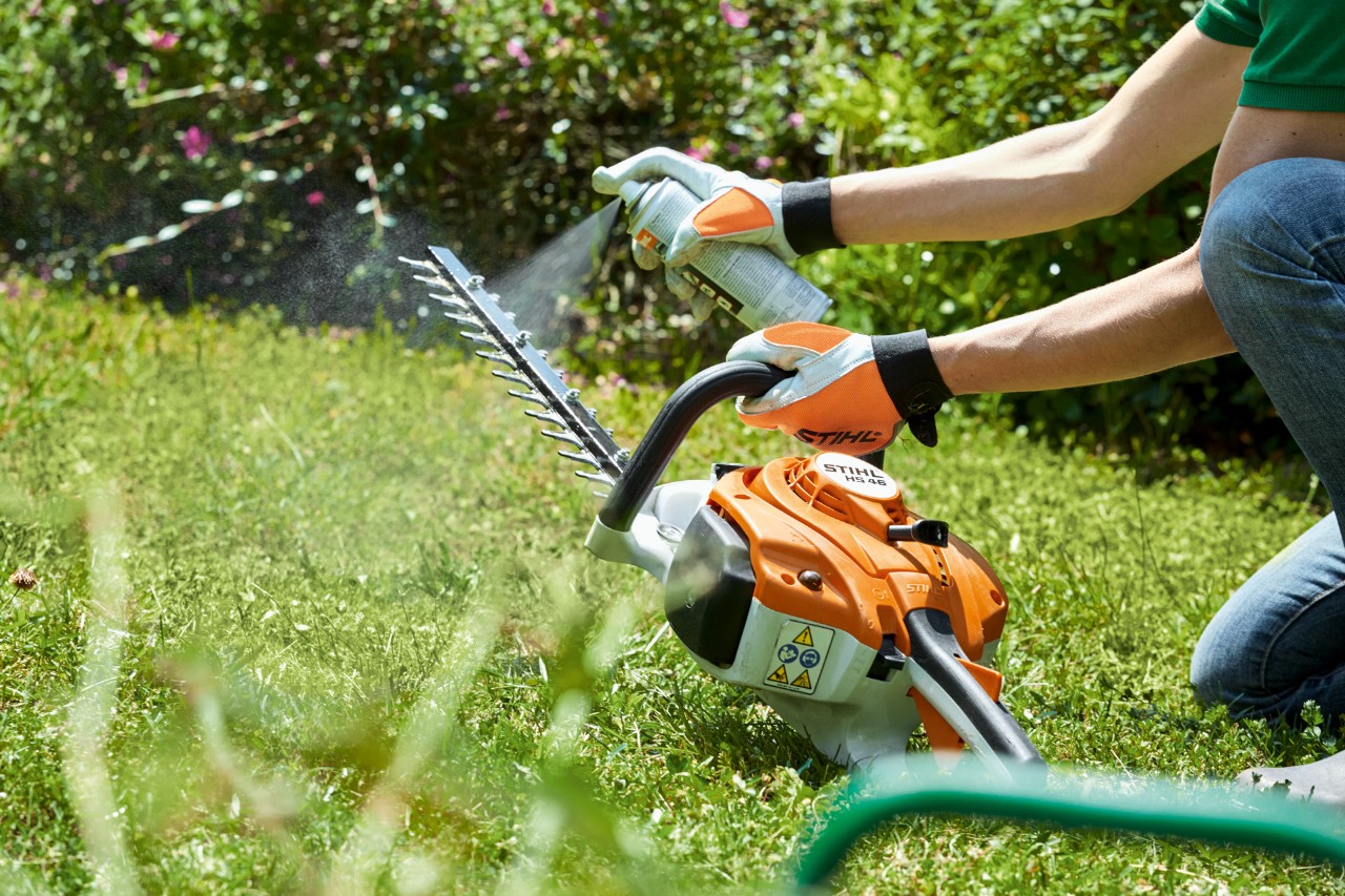  Spraying a STIHL HS 82 T petrol hedge trimmer on a green lawn to clean it