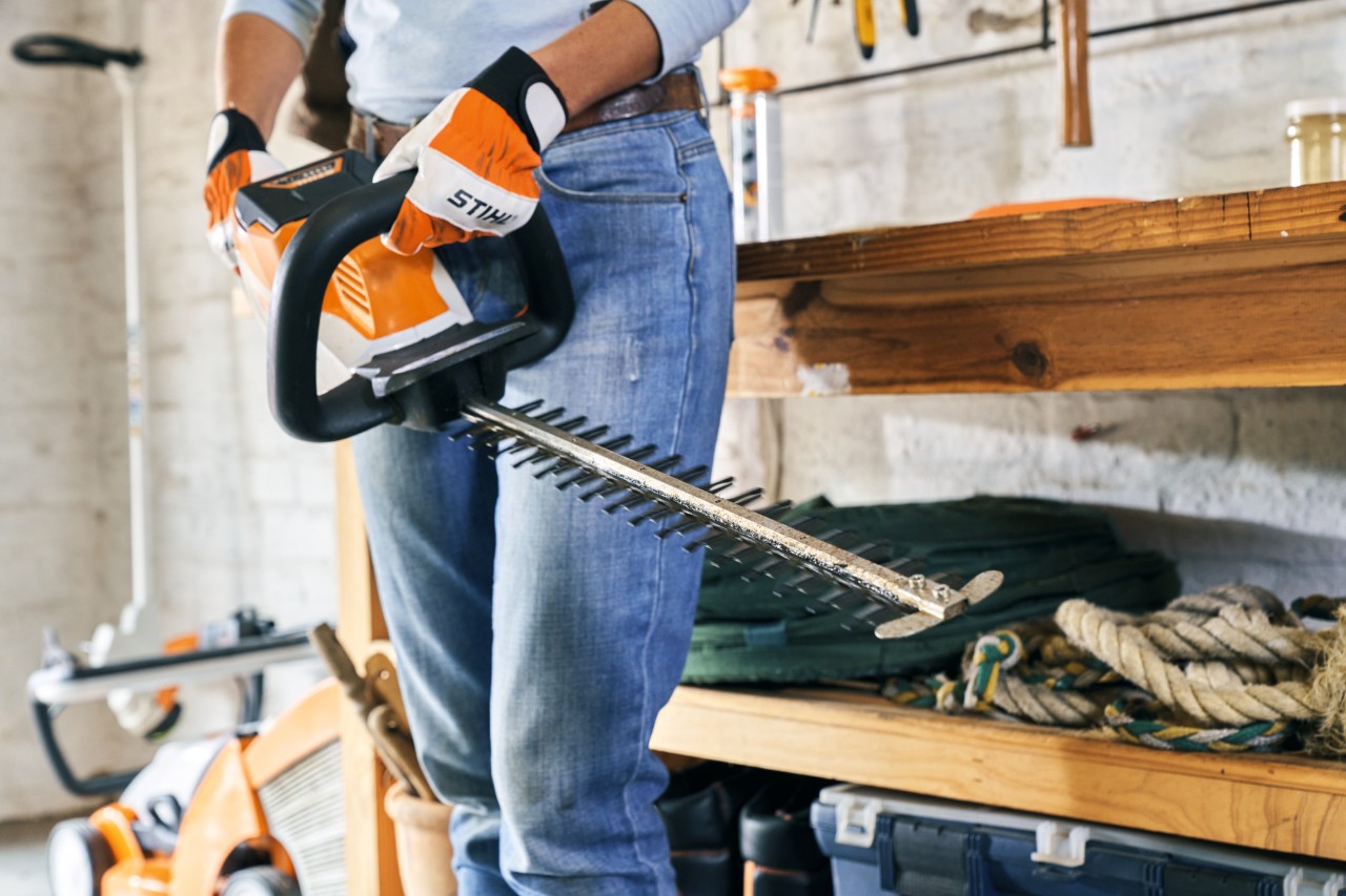 Woman holds a STIHL HSA 56 battery hedge trimmer