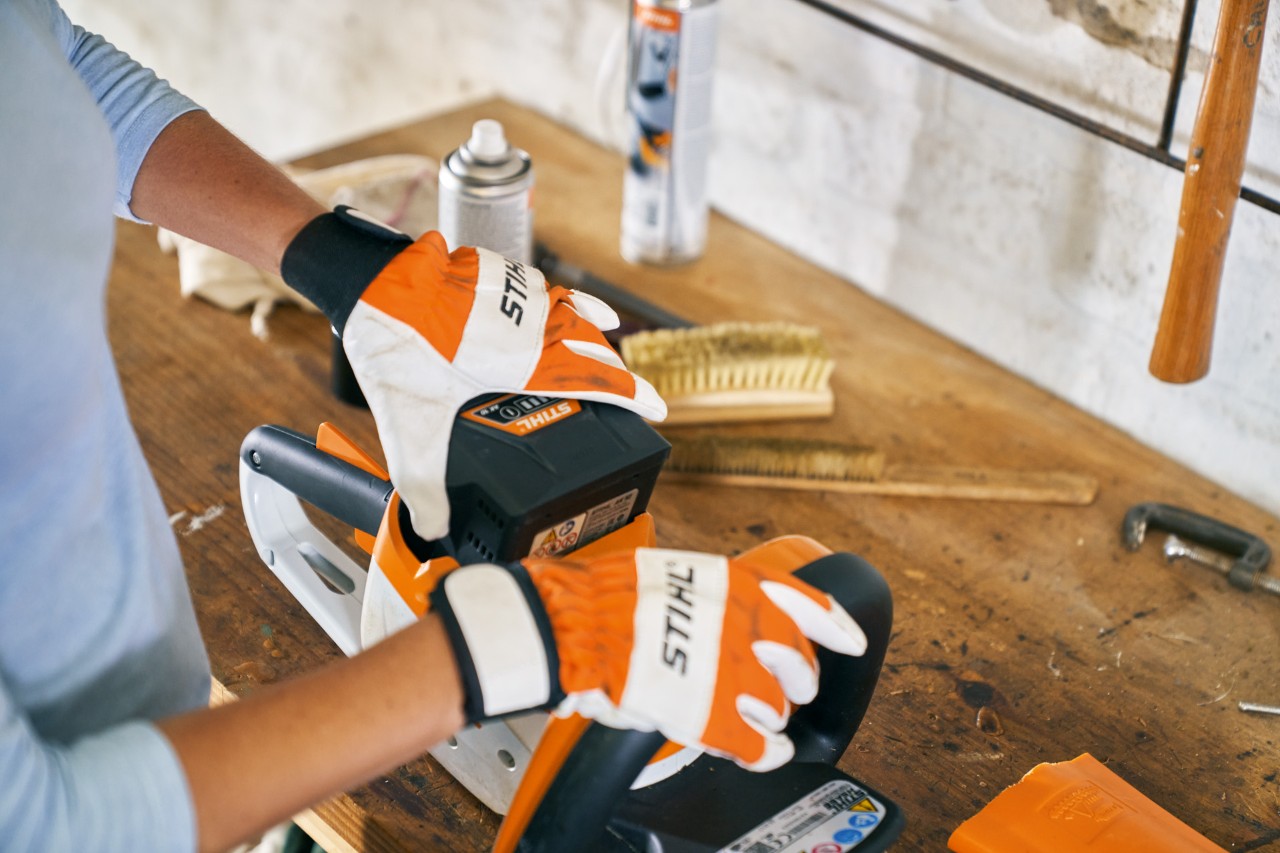 Person works with gloves on the STIHL HSA 56 cordless hedge trimmer